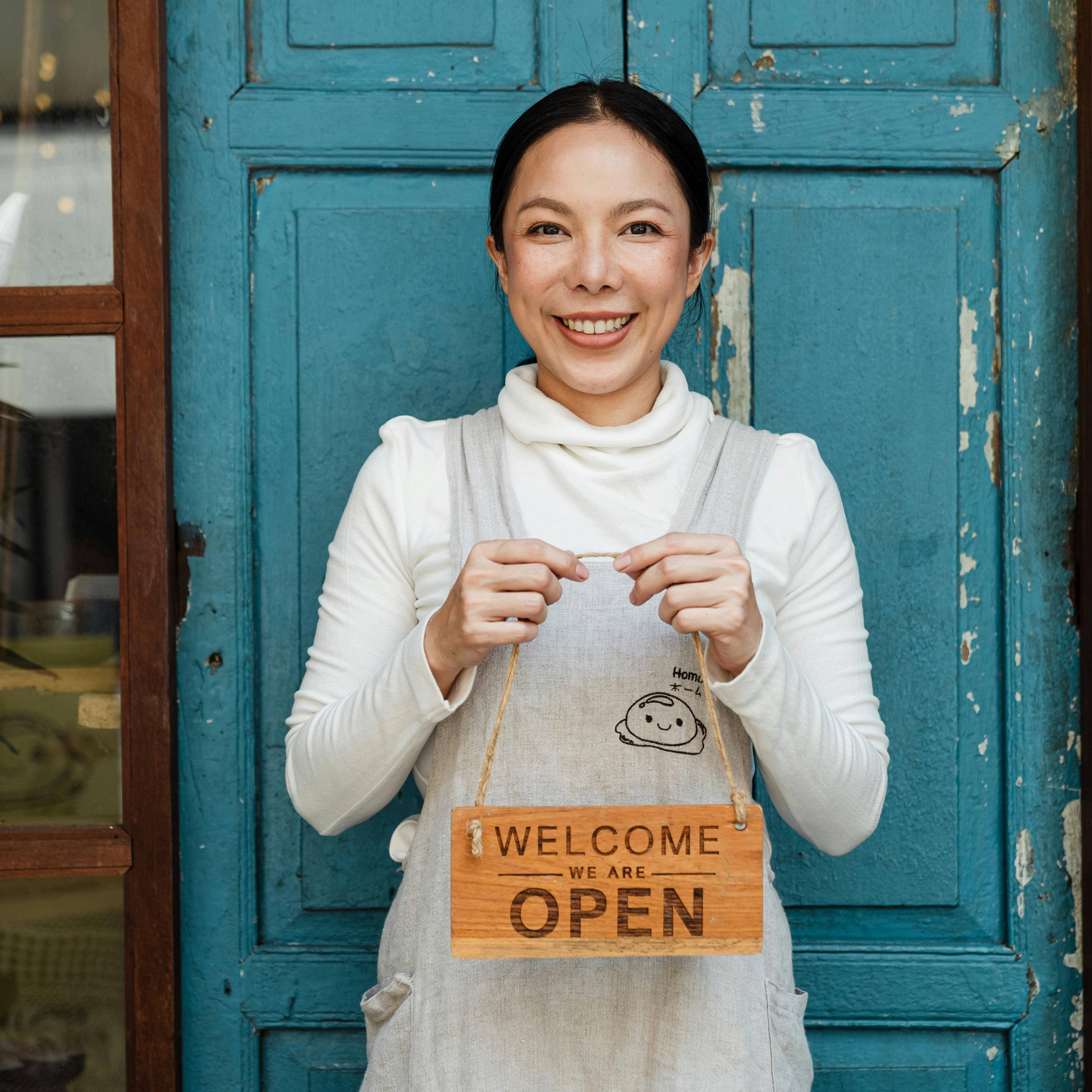 woman holding a welcome we are open sign